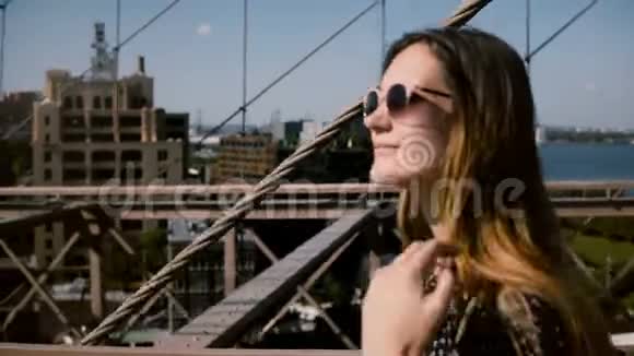 镜头跟随美丽快乐的欧洲黑发女商人戴着时尚的太阳镜走在布鲁克林大桥4K视频的预览图