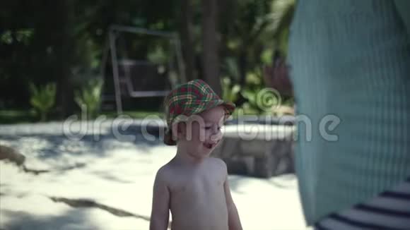 戴着帽子的快乐小男孩去沙滩上找妈妈给她吃水果视频的预览图