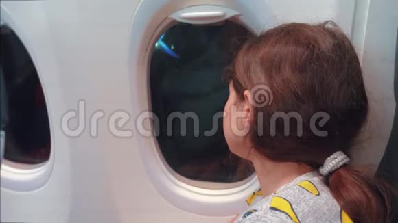 航空飞机概念年轻的十几岁的女孩看着飞机在夜间的窗户飞行年轻乘客视频的预览图
