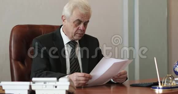 一个头发灰白的成年商人在文件上签名视频的预览图