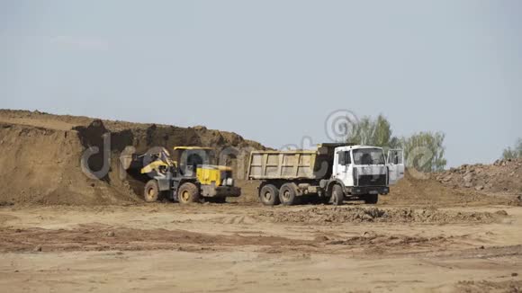 推土机在施工现场装载运砂车建筑设备履带式推土机移动沙子视频的预览图