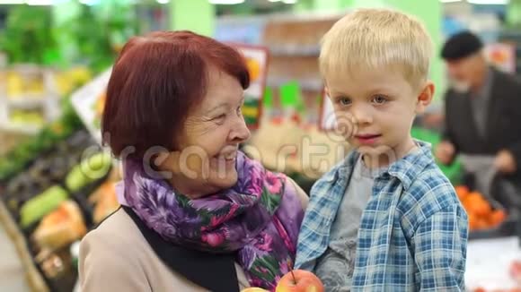 一位老年妇女带着她的小孙子在大型超市买新鲜苹果视频的预览图