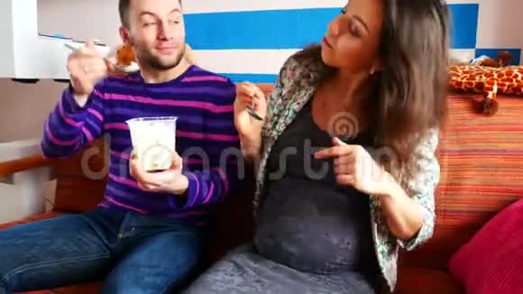 一对年轻夫妇用冰淇淋互相喂饭坐在沙发上视频的预览图