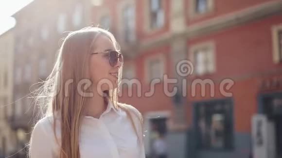 美丽的商务女性带着太阳镜步行穿过城市望着市郊夏季视频的预览图