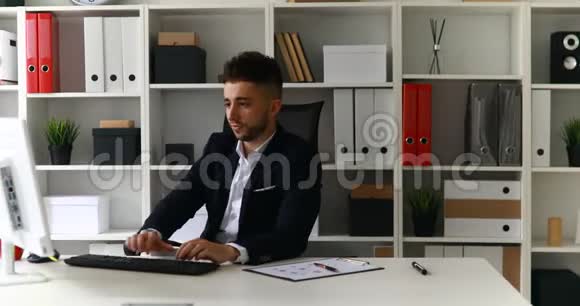 年轻的商人在电脑上工作靠在办公室椅子上视频的预览图