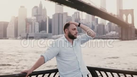 快乐的白种人站在布鲁克林大桥风景的河堤围栏附近反射和欣赏纽约的景色视频的预览图