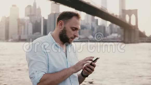严肃的欧洲商人在智能手机信使应用程序上键入信息在惊人的纽约市日落景色4K视频的预览图