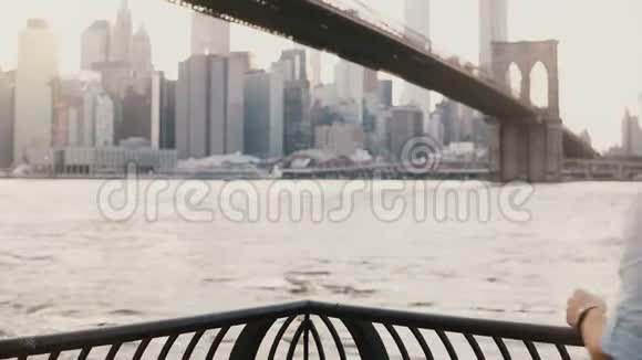 快乐的欧洲男性游客来到纽约布鲁克林大桥附近的河堤拍照并微笑4K视频的预览图