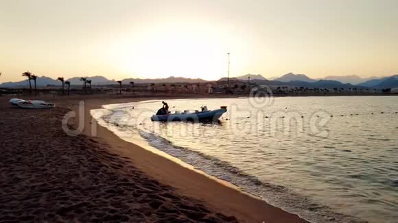 日落时平静海波上装有马达的充气船4k剪影视频视频的预览图