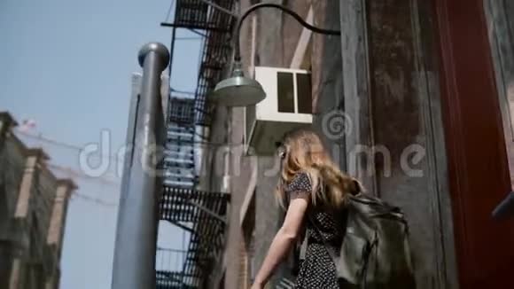 年轻女孩戴着太阳镜背着背包走下红砖建筑的老楼梯慢悠悠地走着视频的预览图