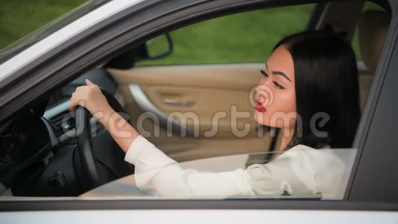 一幅美丽快乐的女人坐在车里对着镜头调情的肖像在交通堵塞中和另一个汽车司机交谈视频的预览图