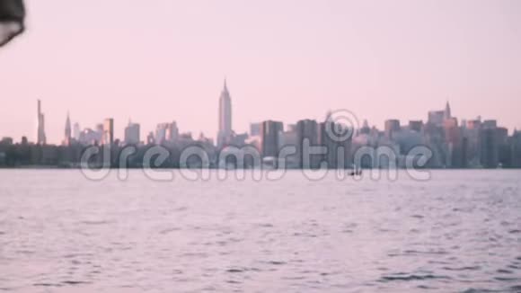戴太阳镜的漂亮女孩坐在水边看着纽约的风景在日落时慢动作视频的预览图