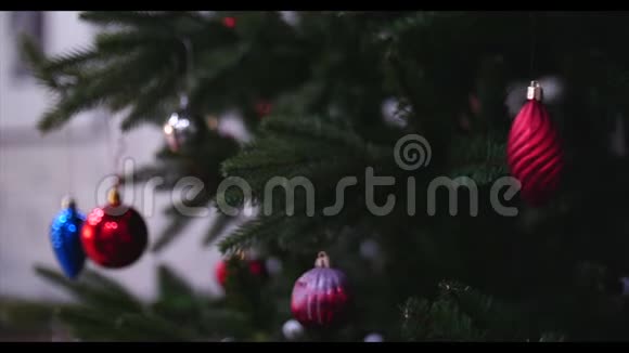 把圣诞装饰品挂在有圣诞灯的树上小女孩的手装饰圣诞树特写视频的预览图