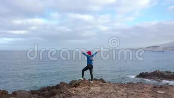 慢跑后穿运动服的女士站在岩石上欣赏保护区的风景视频的预览图