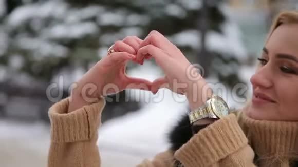 双手捧着心的女孩在冬季公园散步视频的预览图