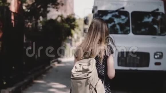 镜头跟随年轻的女游客背包穿过白色货车附近的街道享受休闲步行慢动作视频的预览图