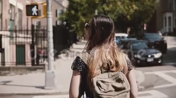 镜头跟随女孩背着背包走在阳光明媚的纽约街过着休闲快乐的生活方式慢动作视频的预览图