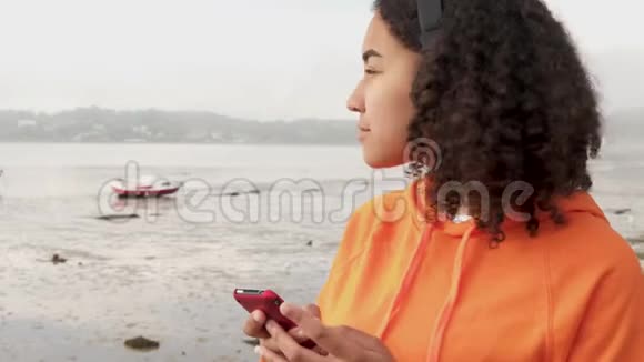 使用智能手机用无线耳机听音乐的混血女青少年视频的预览图