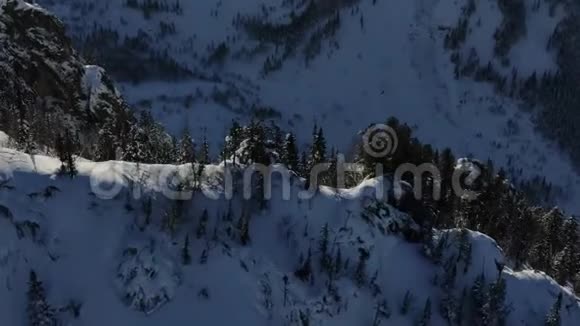 空中无人机绕着森林中雪山上的悬崖移动视频的预览图