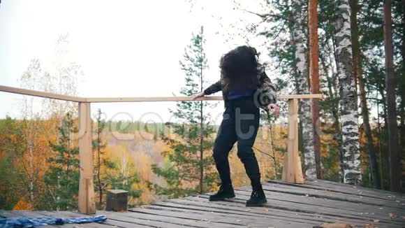 快乐的年轻女子在平台上跳舞会飞的头发背景上的森林慢动作视频的预览图