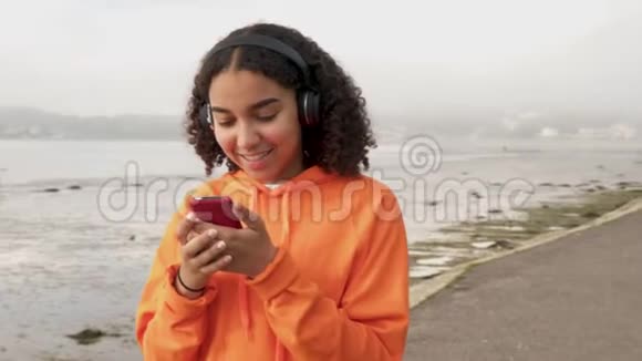 使用智能手机用无线耳机听音乐的混血女青少年视频的预览图