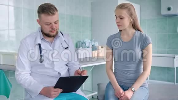 年轻有魅力的男医生在医院或医疗办公室与女病人交谈视频的预览图