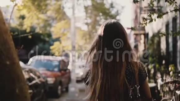 后景快乐的白种人女孩带着飞扬的头发走在阳光明媚的城市街道上生活随意的生活方式慢动作视频的预览图