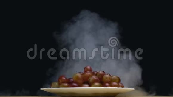 一盘葡萄在黑色背景下缓慢运动的烟雾中旋转视频的预览图