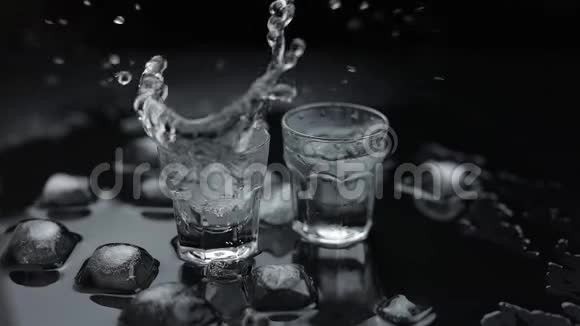 加入冰块在黑色背景下的玻璃中注入伏特加酒精饮料视频的预览图