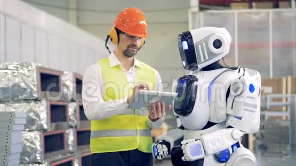 男工与机器人交谈在平板电脑上显示信息然后在机器人显示器上键入信息4K视频的预览图