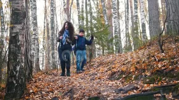 一个年轻的女人和一个男孩在斯堪的纳维亚漫步在森林里一路下坡视频的预览图