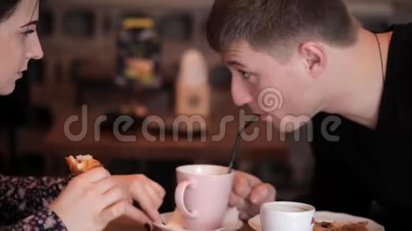 可爱的夫妇在咖啡馆里聊天吃羊角面包和三明治喝咖啡饮料视频的预览图