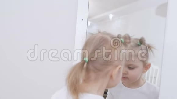 坐在镜子前的可爱的小女孩正在用卫生的口红涂嘴唇视频的预览图