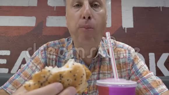 一个中年男人正在咖啡馆里吃午饭他吃汉堡包喝奶昔视频的预览图