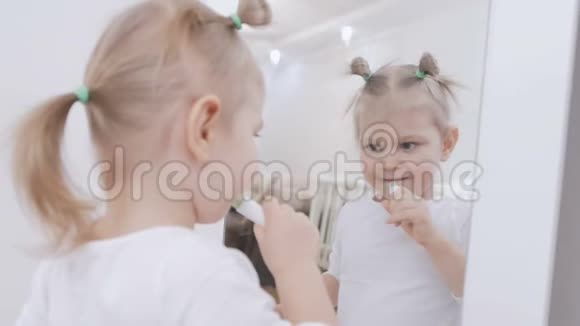 坐在镜子前的可爱的小女孩正在用卫生的口红涂嘴唇视频的预览图