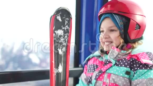 十几岁的女孩戴着头盔带着滑雪板爬上滑雪缆车舱的一座山滑雪胜地家庭滑雪视频的预览图