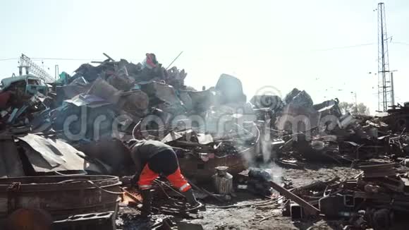 工人在废料场上用煤气切割器切割金属以回收利用视频的预览图