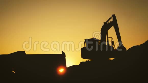 日落时将沙子装入卡车的挖掘机剪影概念建设和重工业机器意志视频的预览图