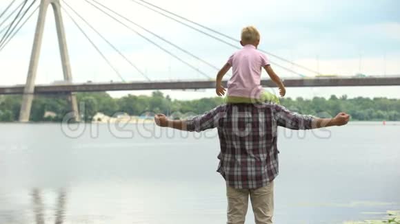 爸爸带着儿子在肩膀上看着城市表现出力量和信心视频的预览图