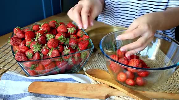 双手合拢剥下新鲜的大草莓供以后使用视频的预览图