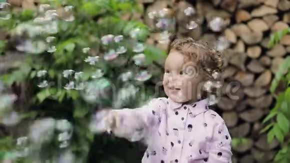 小卷曲的女孩玩肥皂泡感觉快乐慢动作泡泡秀视频的预览图