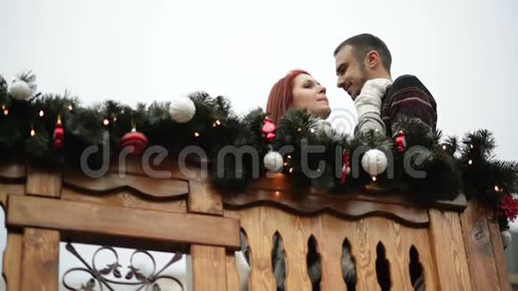 圣诞节年轻夫妇在木制阳台装饰的假日浪漫的约会市政厅视频的预览图