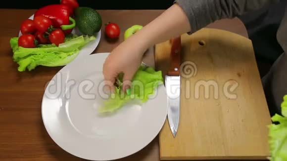 一个女人把绿生菜叶放在白色盘子里视频的预览图