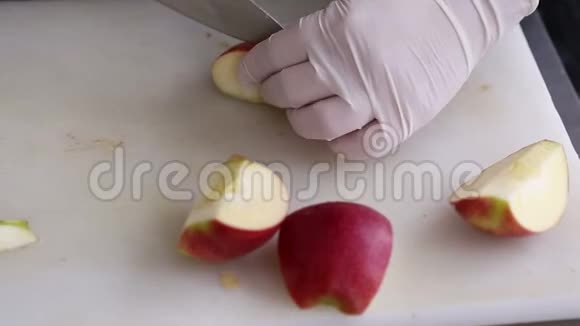 一个带着厨房手套的厨师用刀子把苹果切成薄片视频的预览图