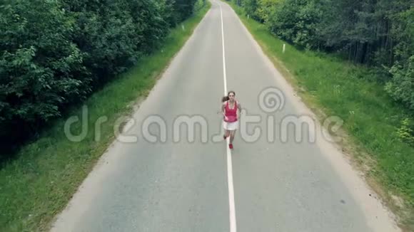 焦点正在远离一个苗条漂亮的女人在小巷里慢跑空中飞行视频的预览图