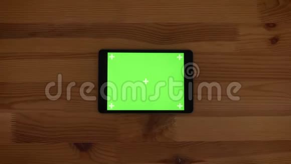 慢慢放大水平平板电脑的顶部镜头绿色屏幕上的木制桌子背景视频的预览图