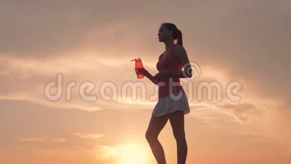阳光明媚的风景一位美丽的年轻女士从瓶子里喝酒视频的预览图