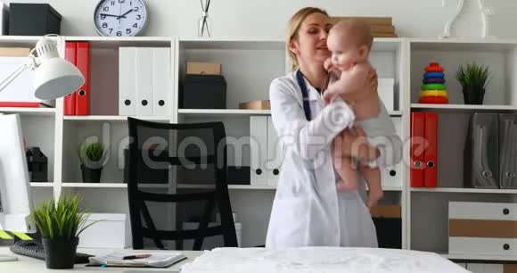 儿科医生把微笑的婴儿抱在怀里看着镜头视频的预览图