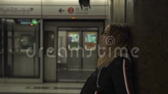 在地铁站站台上等候火车的旅游妇女地下旅行的年轻女子城市交通旅费视频的预览图