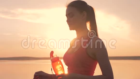 靠近一位漂亮的年轻女士打开一个瓶子从瓶子里喝下去视频的预览图
